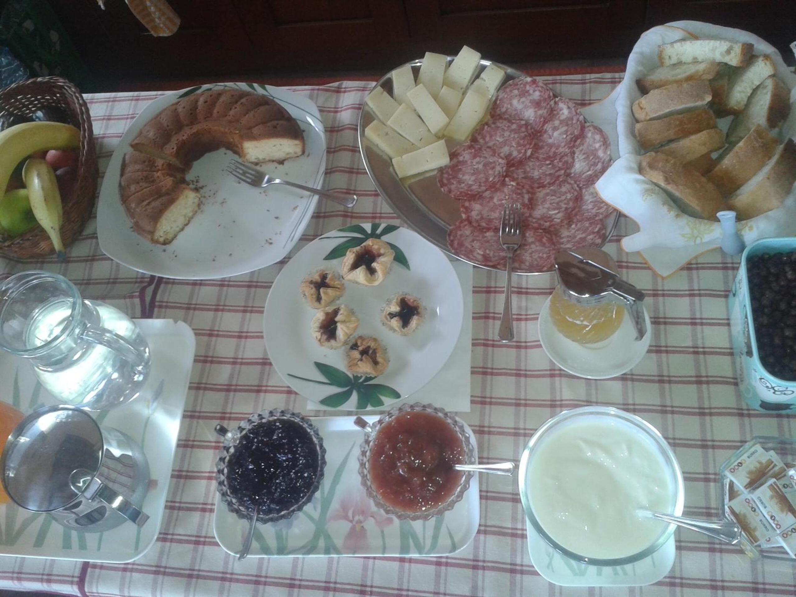Une table sur laquelle on trouve divers aliments, notamment un gâteau, du fromage, du pain et des condiments.