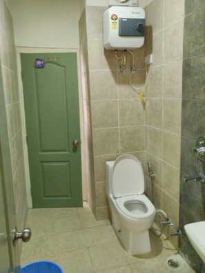 A small bathroom with a toilet, a water heater, and a shower. - Cottages at Village (Nainital)