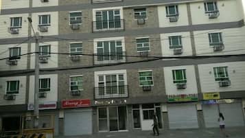 Um edifício de vários andares com vários espaços comerciais no térreo, incluindo uma vitrine com uma placa.