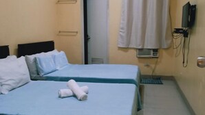 Habitación de hotel con dos camas, un televisor montado en la pared y una ventana con cortina.
