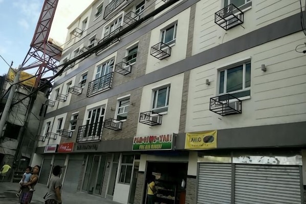 A multi-story building with several storefronts, including a visible sign for a restaurant.