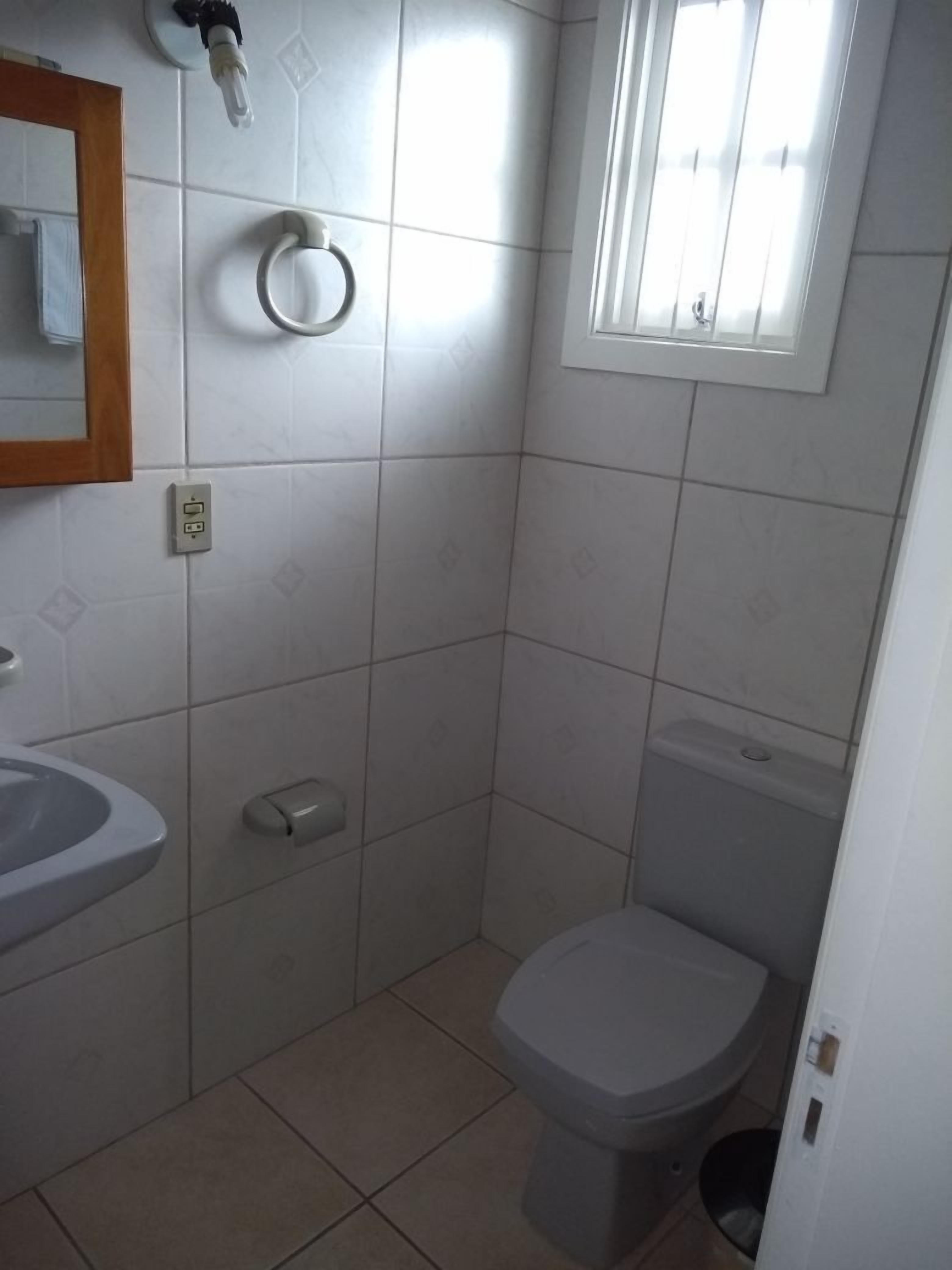 A small, clean bathroom with a toilet, sink, and a mirror.
