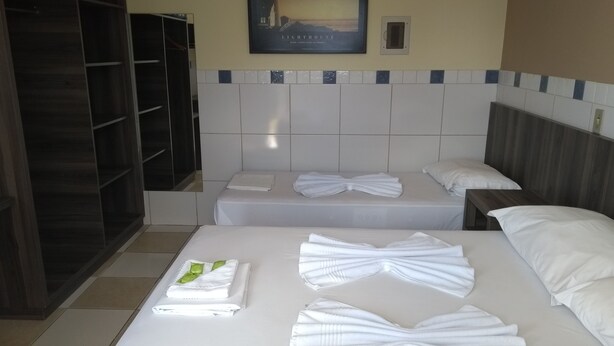 Una habitación de hotel con dos camas, un armario y un cuadro en la pared.
