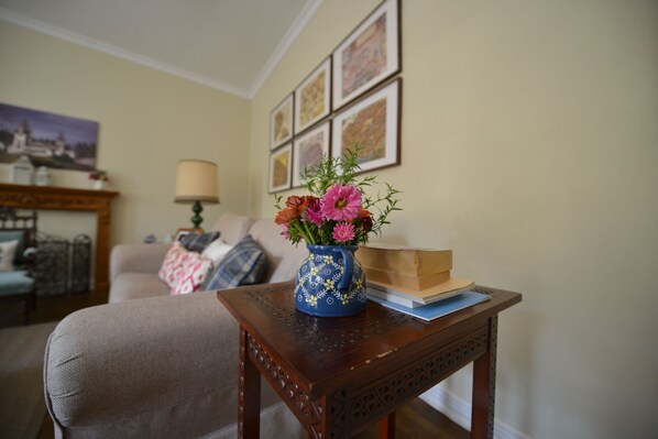 Un salón con una mesita de madera que sostiene un florero con flores y un libro.