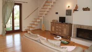 A living room with a wooden staircase, a fireplace, a television, and a sofa. - Agriturismo Pian di Frattina (Fabro)