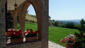 A stone archway leading to a garden with potted plants and a view of a green landscape. - Agriturismo Pian di Frattina (Fabro)