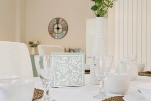 A dining table with white plates, glasses, and a vase with green leaves. - HomeAway B&B (Salerno)