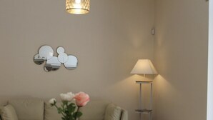 A living room with a beige sofa, a side table with a lamp, and a wall-mounted mirror arrangement. - HomeAway B&B (Salerno)