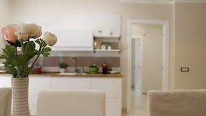 A modern kitchen with white cabinets and a dining area with a white table and chairs. - HomeAway B&B (Salerno)