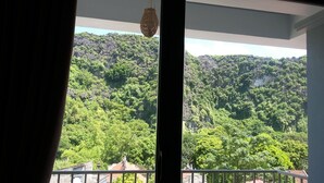 A room with a view of a lush green forested mountain. - Limestone Boutique Hotel (Ninh Binh)