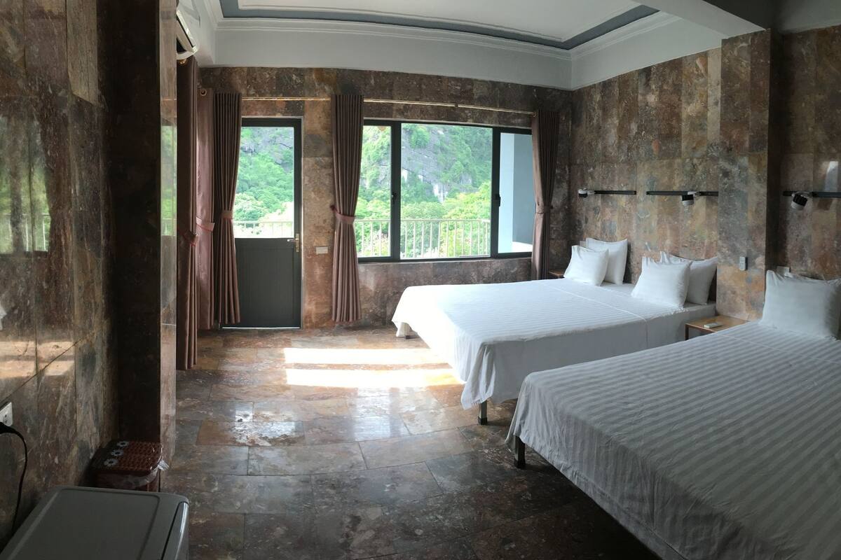 Habitación de hotel con dos camas, una mesita, una silla y vistas a zonas verdes.