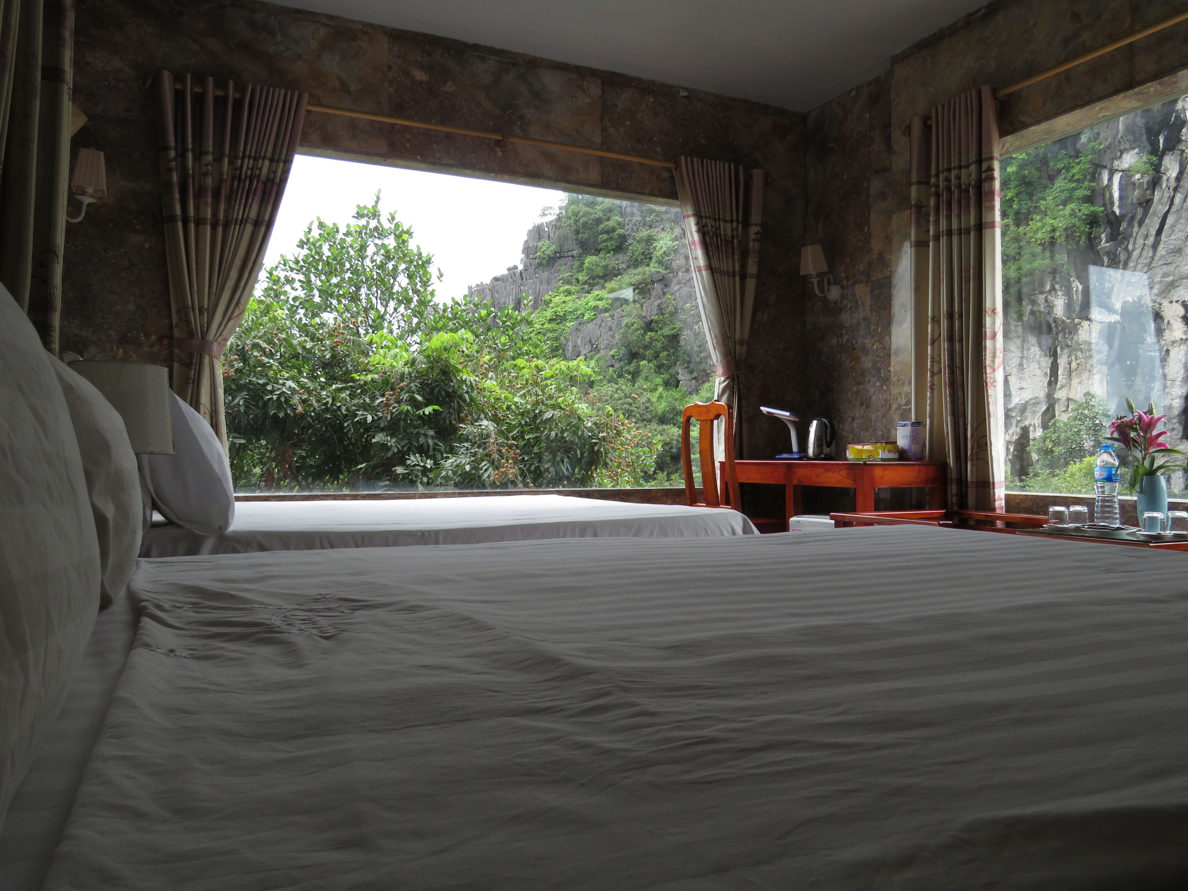 A bedroom with a large bed, a desk, and a view of a mountainous landscape.