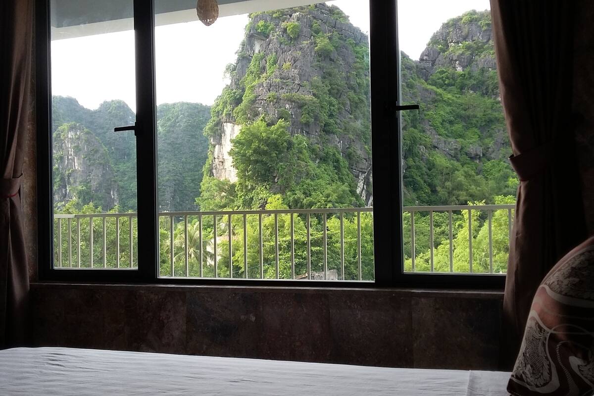 Una habitación con cama y ventana con vistas a un paisaje montañoso.