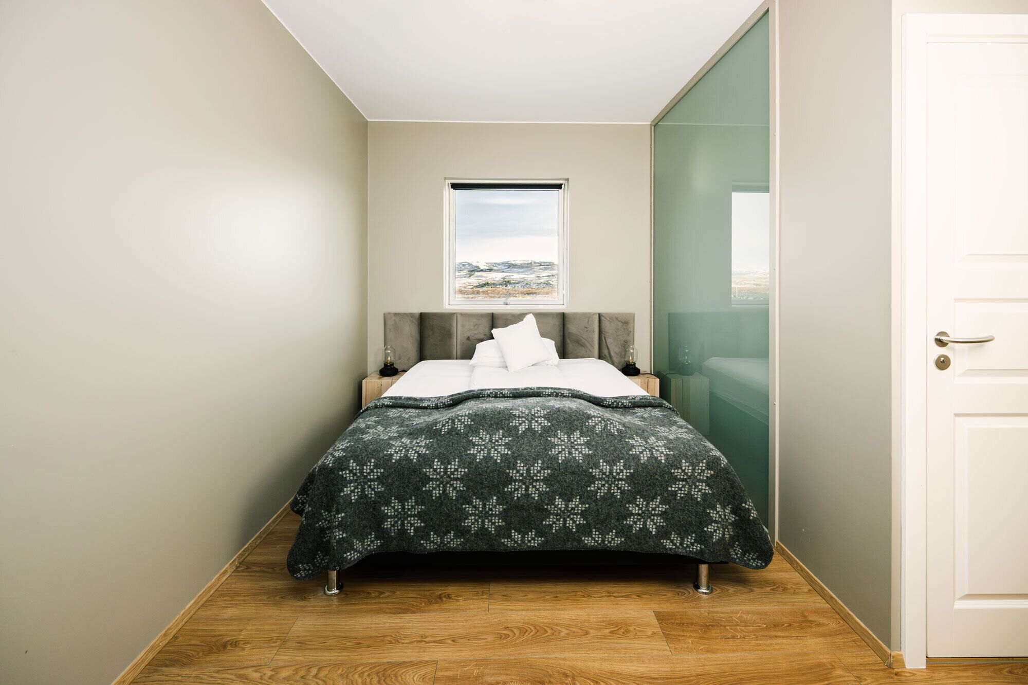Een slaapkamer met een bed, een raam met uitzicht en een deur.