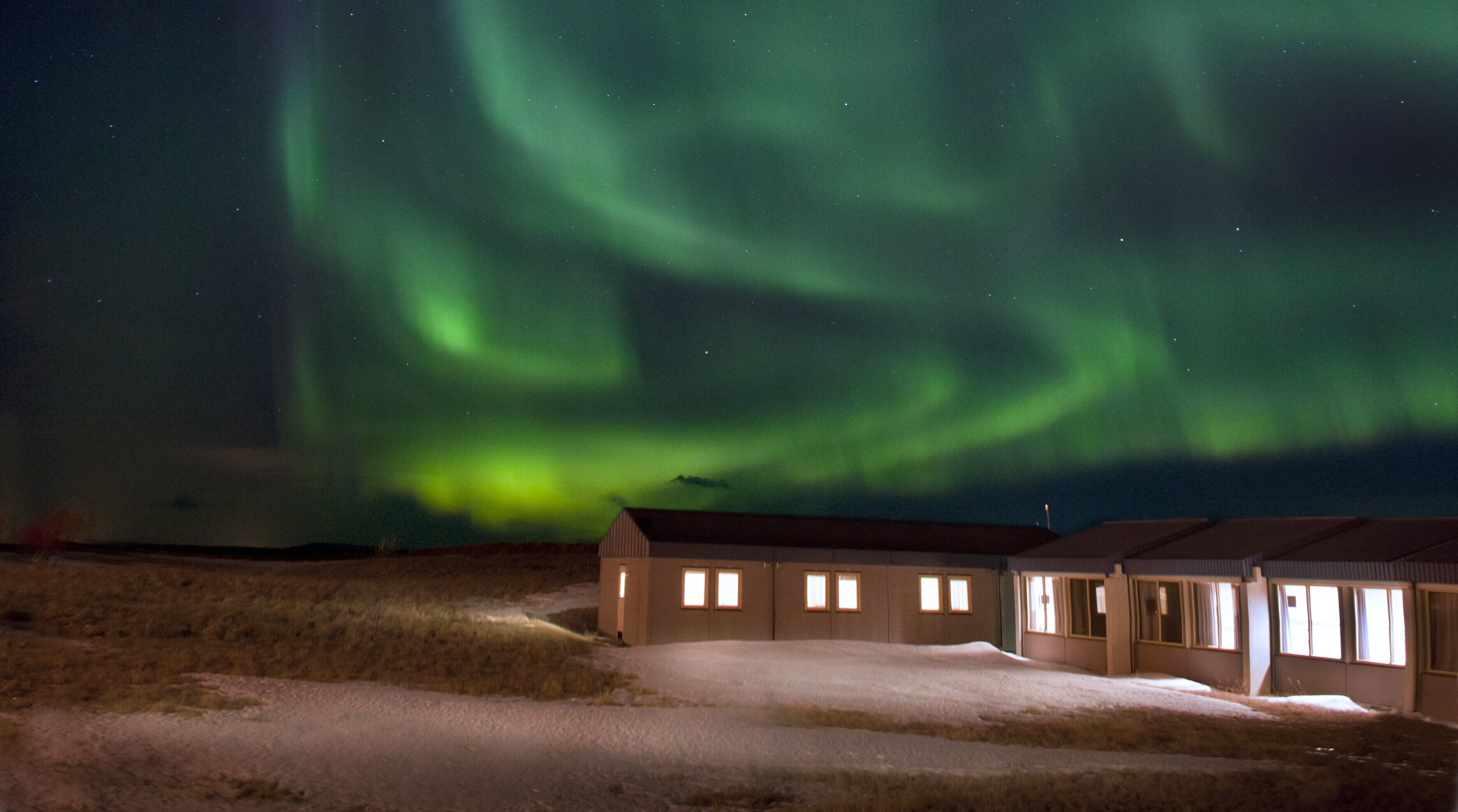 Un bâtiment dont le sol est recouvert de neige et qui offre une vue sur les aurores boréales.