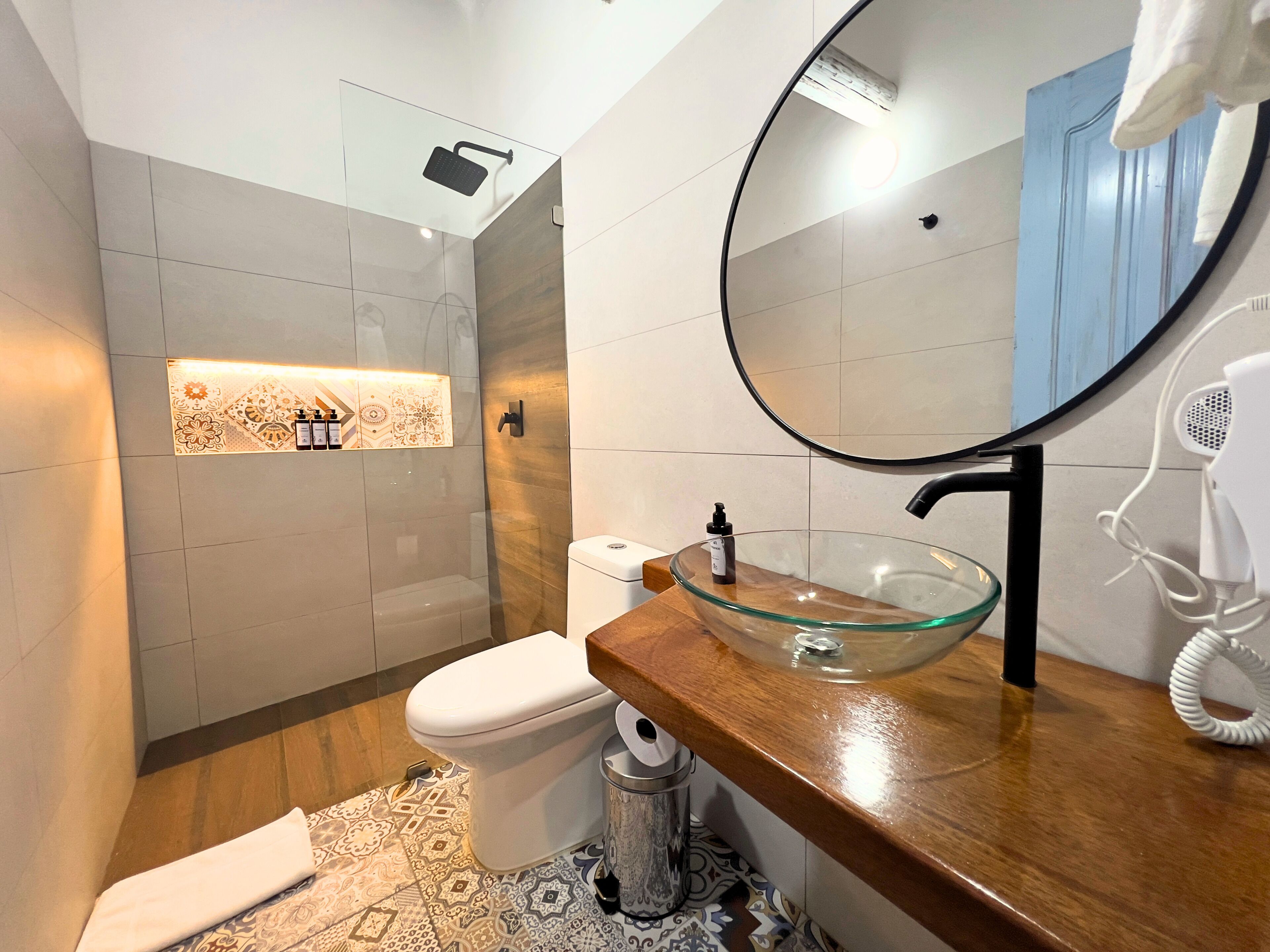 Un baño moderno con un lavamanos de vidrio, inodoro y ducha.