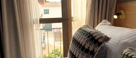 Una habitación de hotel con una cama, una ventana con cortinas y vistas a edificios.
