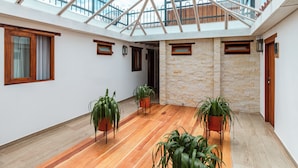 A spacious room with a wooden floor, large windows, and potted plants. - Casa Sie (Villa de Leyva)