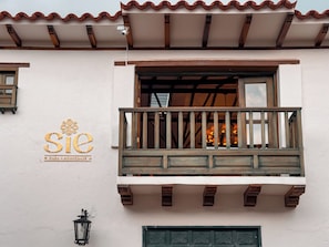 Un edificio con balcón, un letrero que dice 'SIE' y una puerta con detalles decorativos.