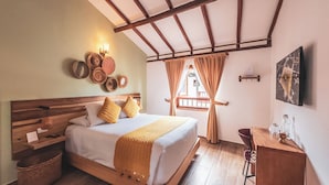 A bedroom with a wooden bed, a nightstand, a desk, a woven throw blanket, and a view of the outside. - Casa Sie (Villa de Leyva)