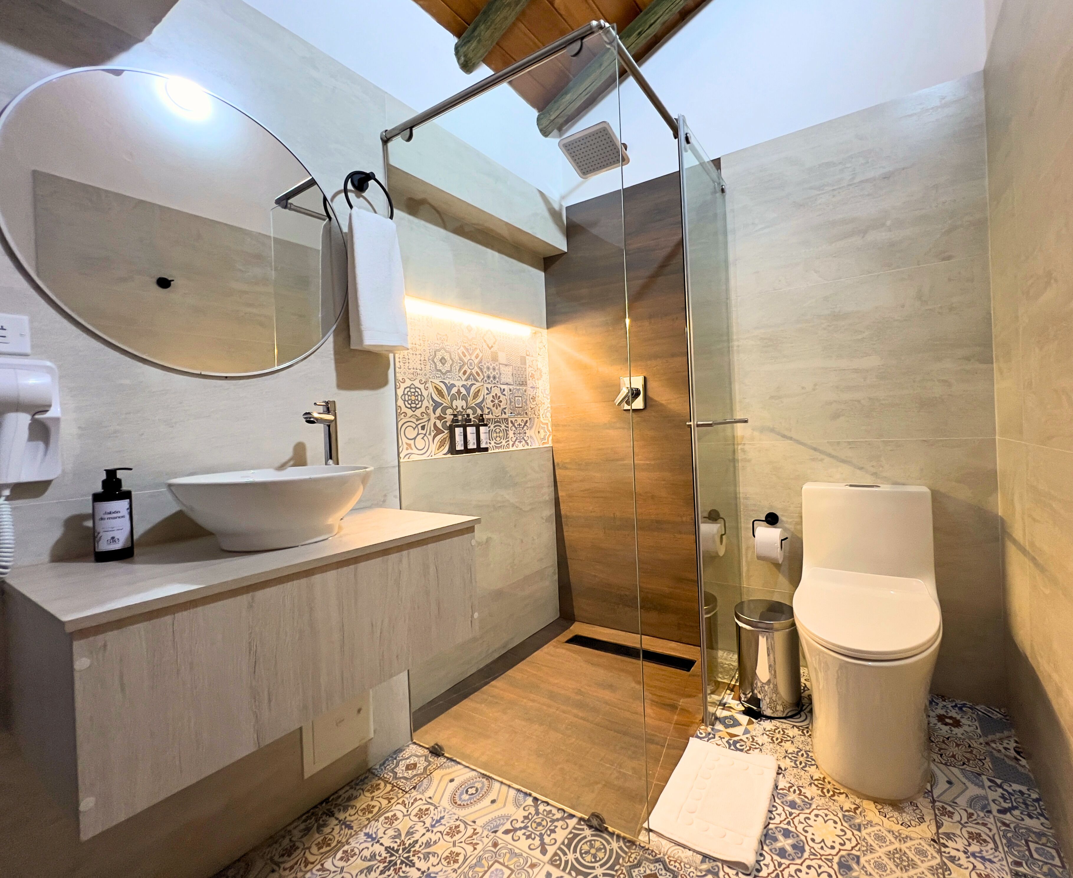 Un baño moderno con un espejo grande, lavamanos, cabina de ducha e inodoro.