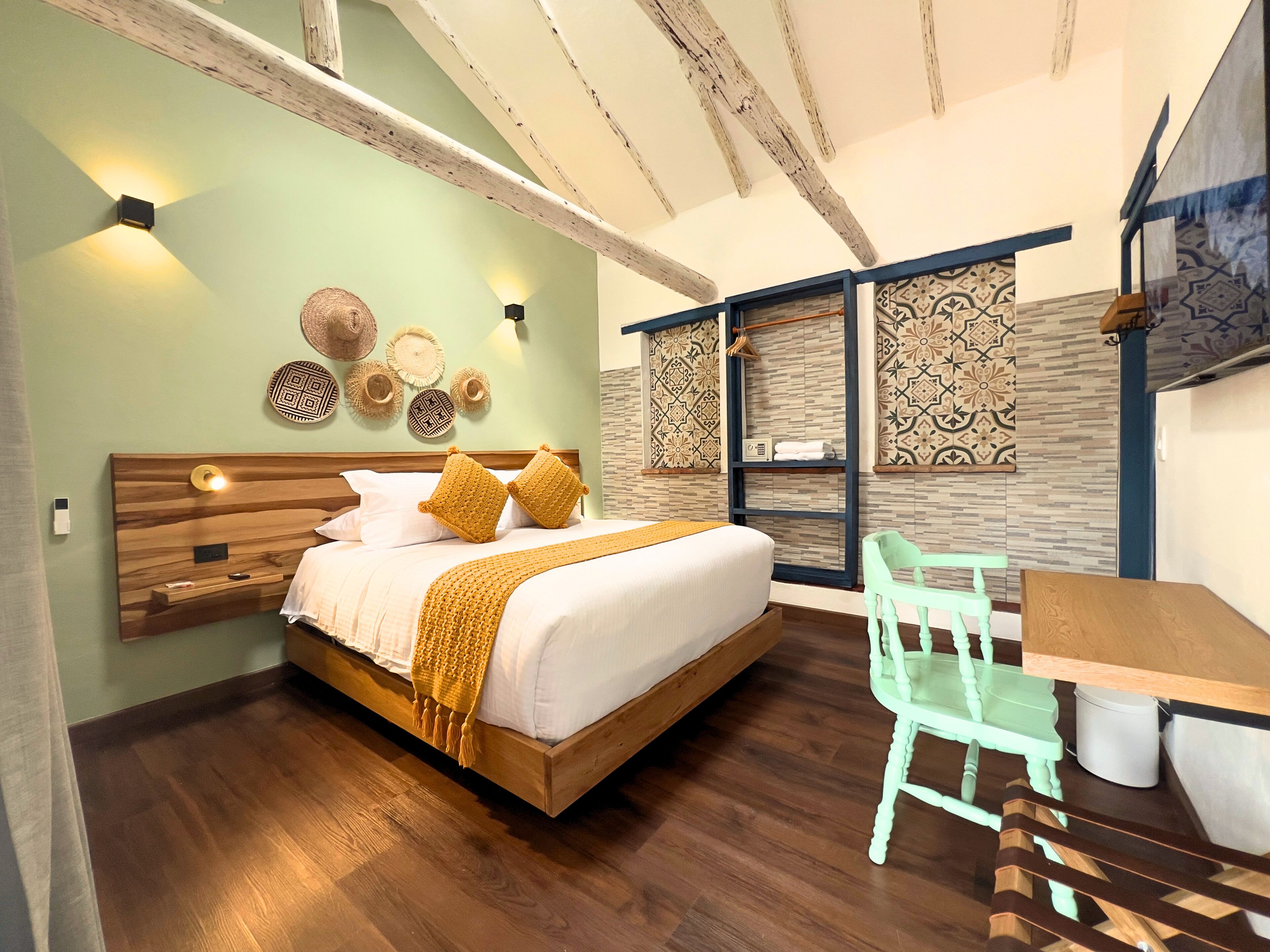 A bedroom with a wooden bed, a green chair, and a desk.