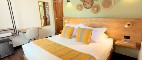 A hotel room with a wooden ceiling, a bed with a yellow and white striped blanket, a nightstand with a lamp, and a wall with woven baskets.