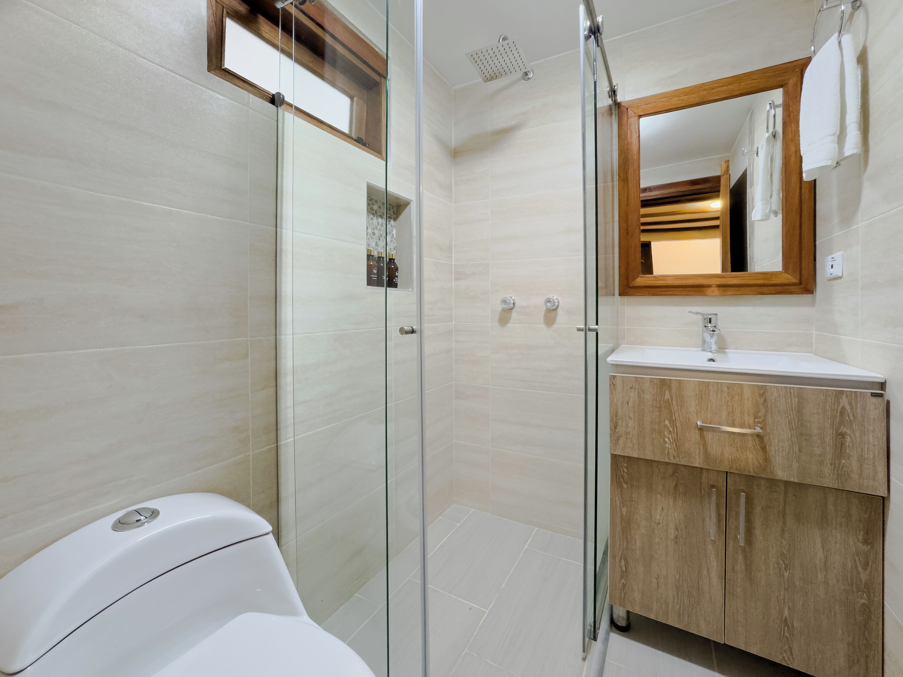 A modern bathroom with a glass shower enclosure, a wooden vanity, and a large mirror.