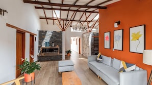 A spacious living area with a stone fireplace, a sofa, a wooden coffee table, and framed artwork on the walls. - Casa Sie (Villa de Leyva)