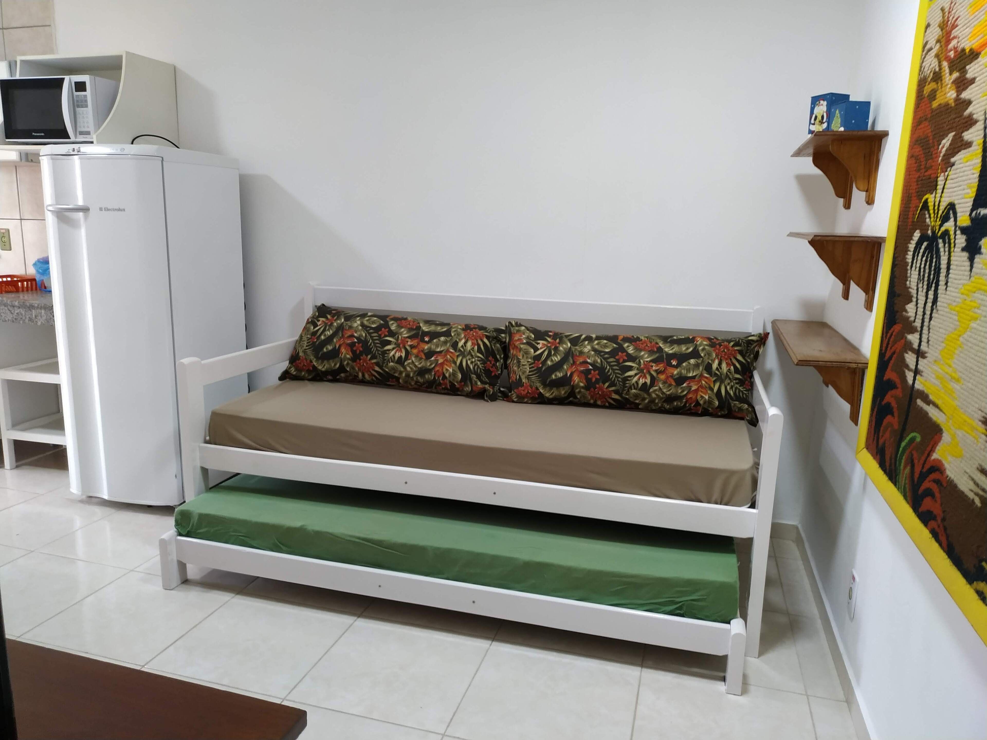 Une pièce de taille modeste, avec un canapé blanc, un four à micro-ondes et un réfrigérateur.