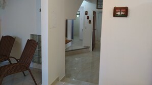 A hallway with a dining area on the left, a mirror, and a door leading to another room. - Residencial Praia Bombas (Bombinhas)