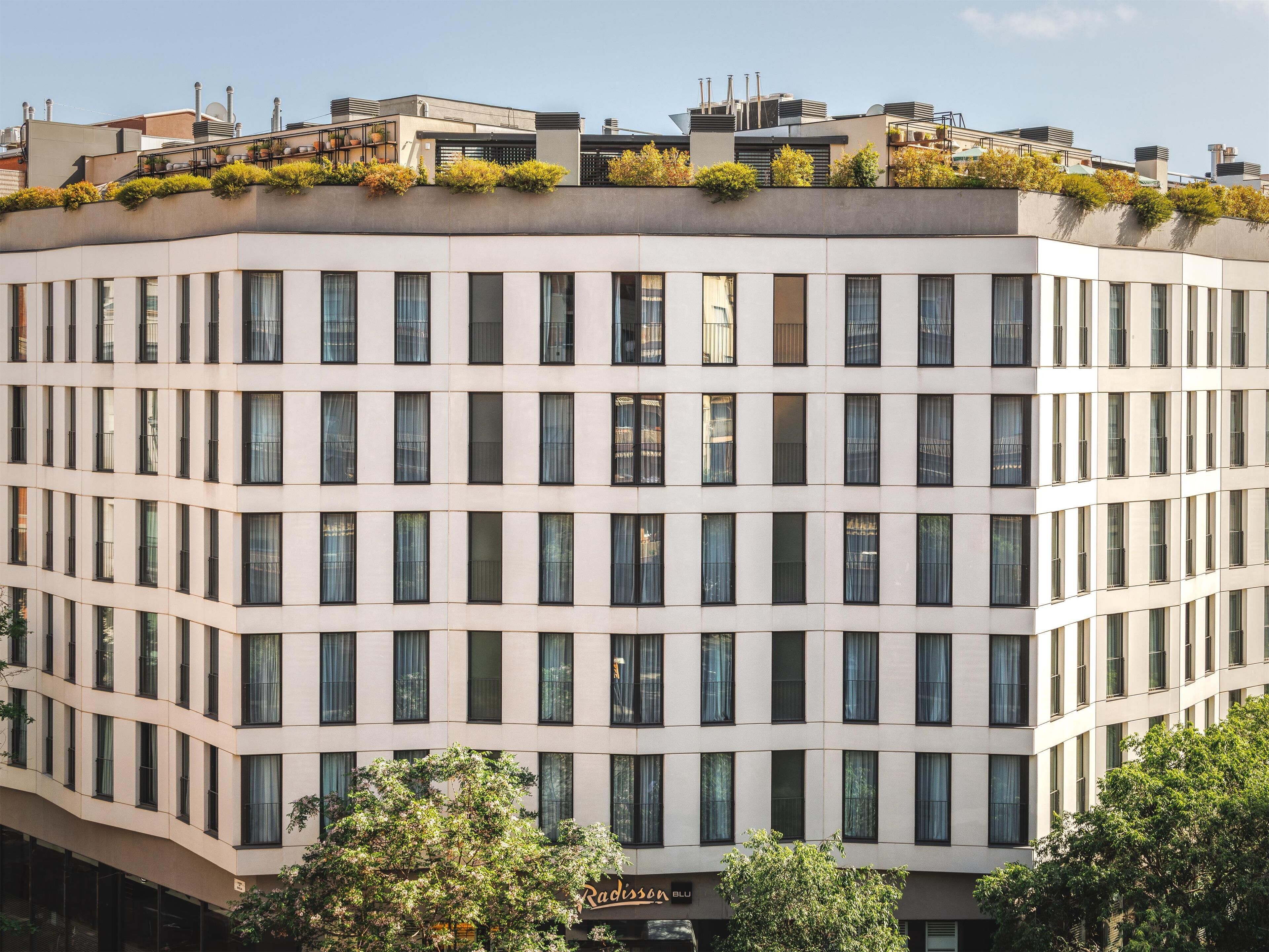 Un edificio de varios pisos con un diseño arquitectónico moderno, que presenta una fachada plana y numerosas ventanas.