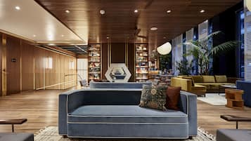 Una sala de estar moderna con un sofá azul, piso de madera y una gran estantería.