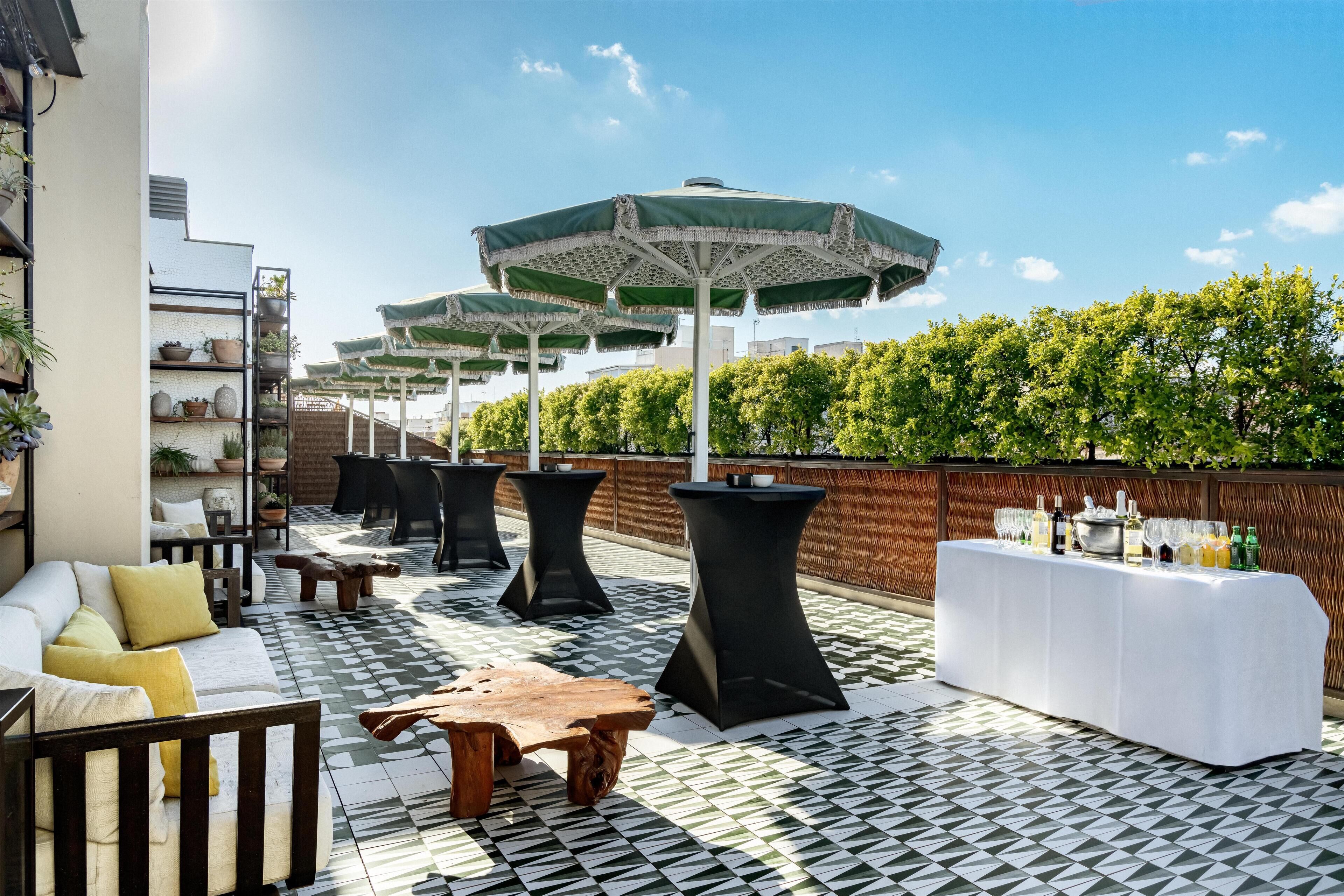 Terraza en la azotea con mesas al aire libre, sombrillas y una zona de bar.