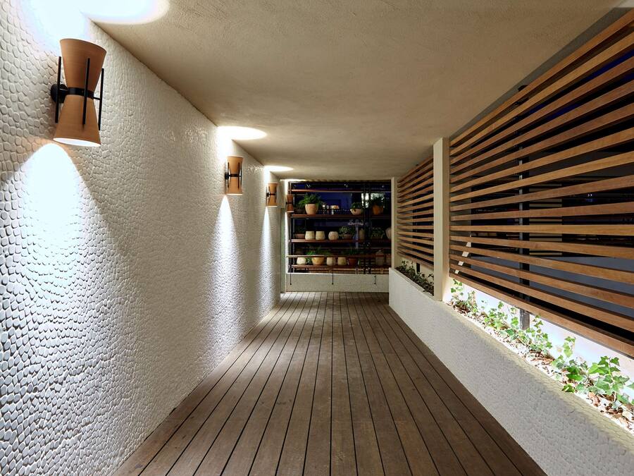 Un pasillo con suelo de madera, paredes blancas con textura y una pared de listones de madera a la derecha.