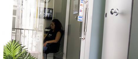 A hotel entrance with a sign reading "NAPOLI Binario 1" and a woman sitting inside.