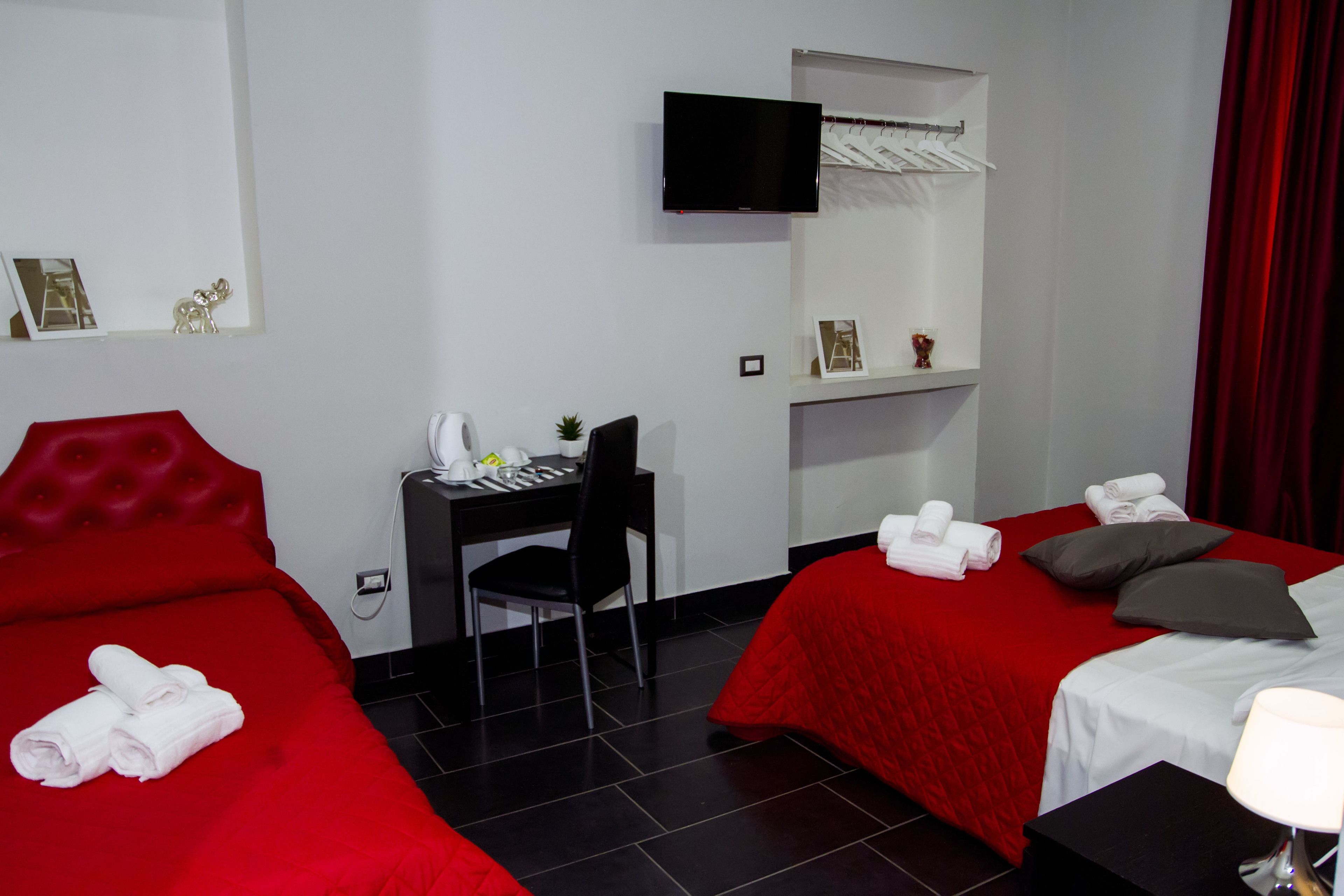 Une chambre d’hôtel avec deux lits, un bureau, une chaise, une télévision et un rideau rouge.
