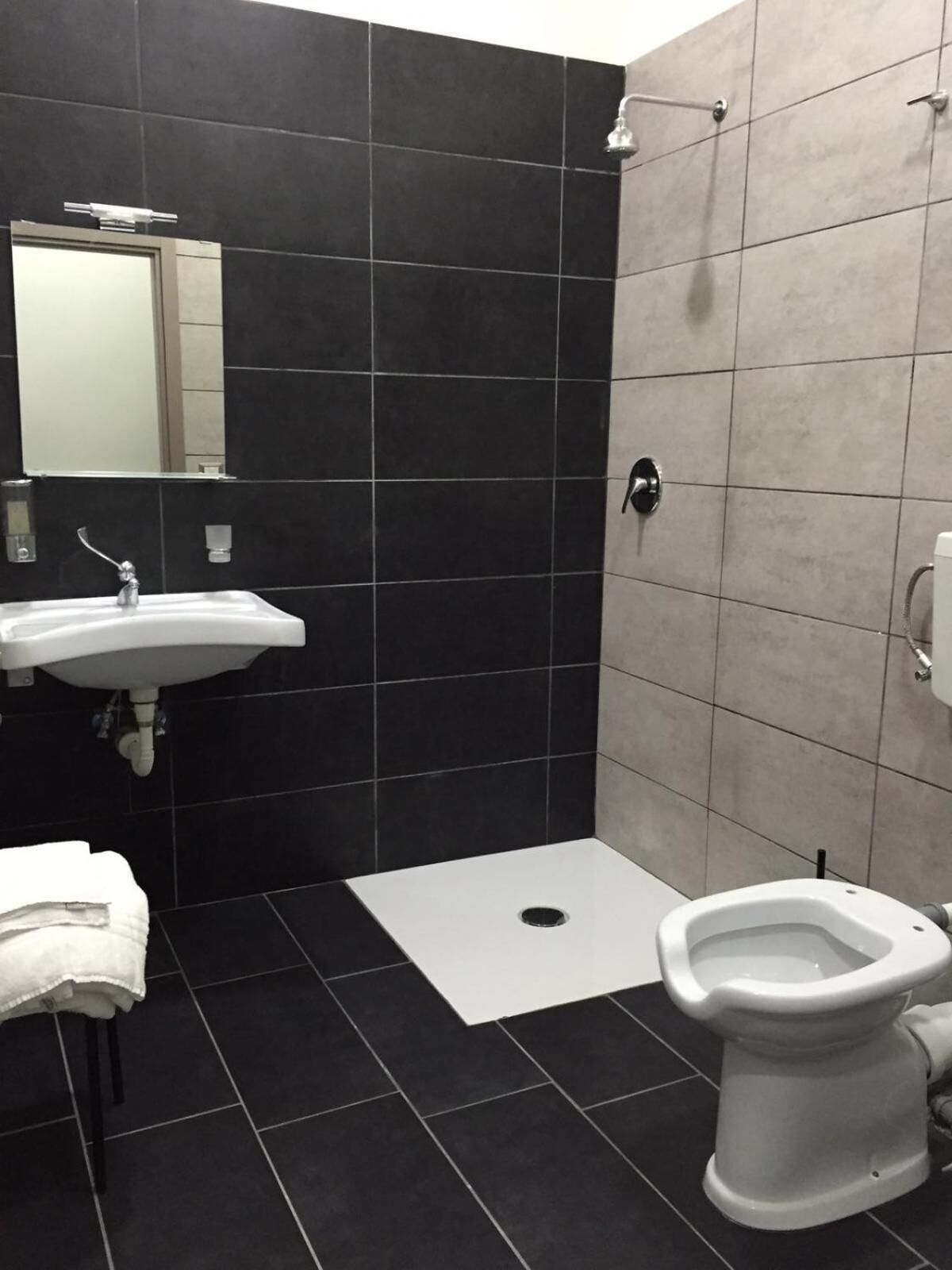 A bathroom with a sink, mirror, toilet, and shower.