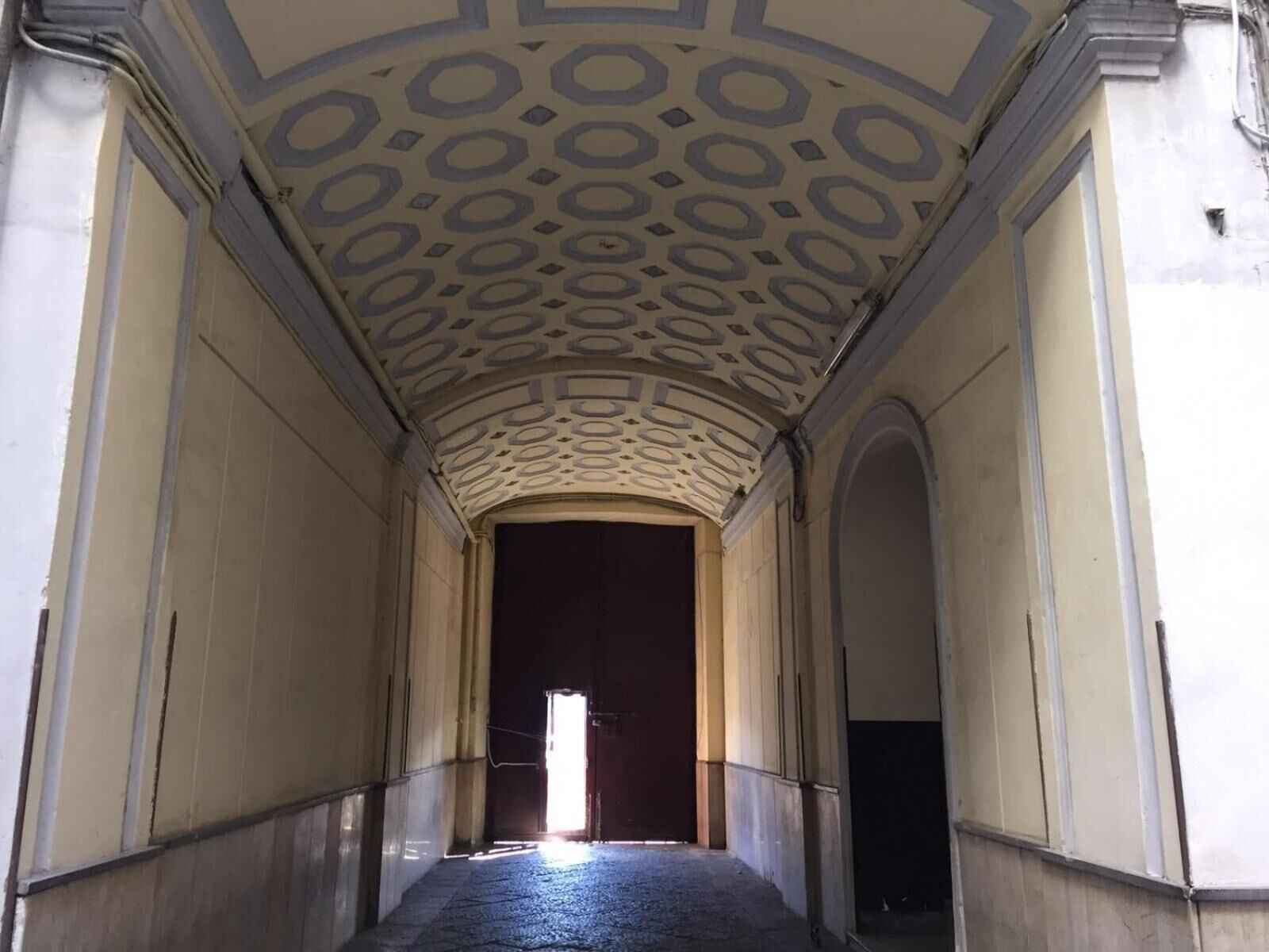 A corridor with a patterned ceiling and arched doorways.