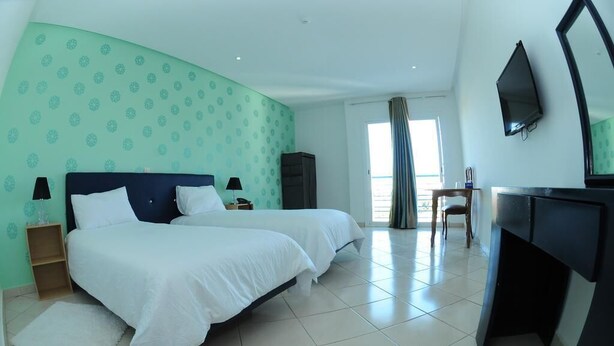 Una habitación de hotel con dos camas, un escritorio, un televisor y un armario.