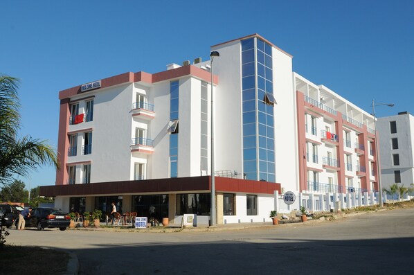 A multi-story hotel with a modern facade, balconies, and a clear sky. - Free Zone Hotel (Hjar Ennhal)