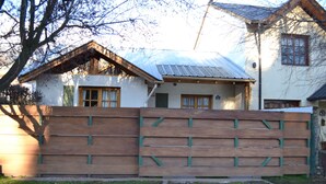 Une clôture en bois devant une maison dont le toit est en métal.