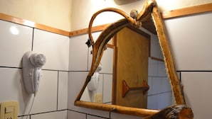 Une salle de bain avec un miroir encadré en bois, un sèche-cheveux et une porte en bois.