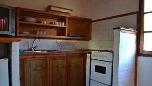 Une cuisine avec des meubles de rangement en bois, une cuisinière et un réfrigérateur.