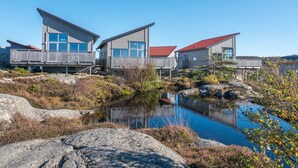 A waterfront property with three modern houses featuring large windows and wooden decks. - Hav & Logi Skärhamn (Skaerhamn)