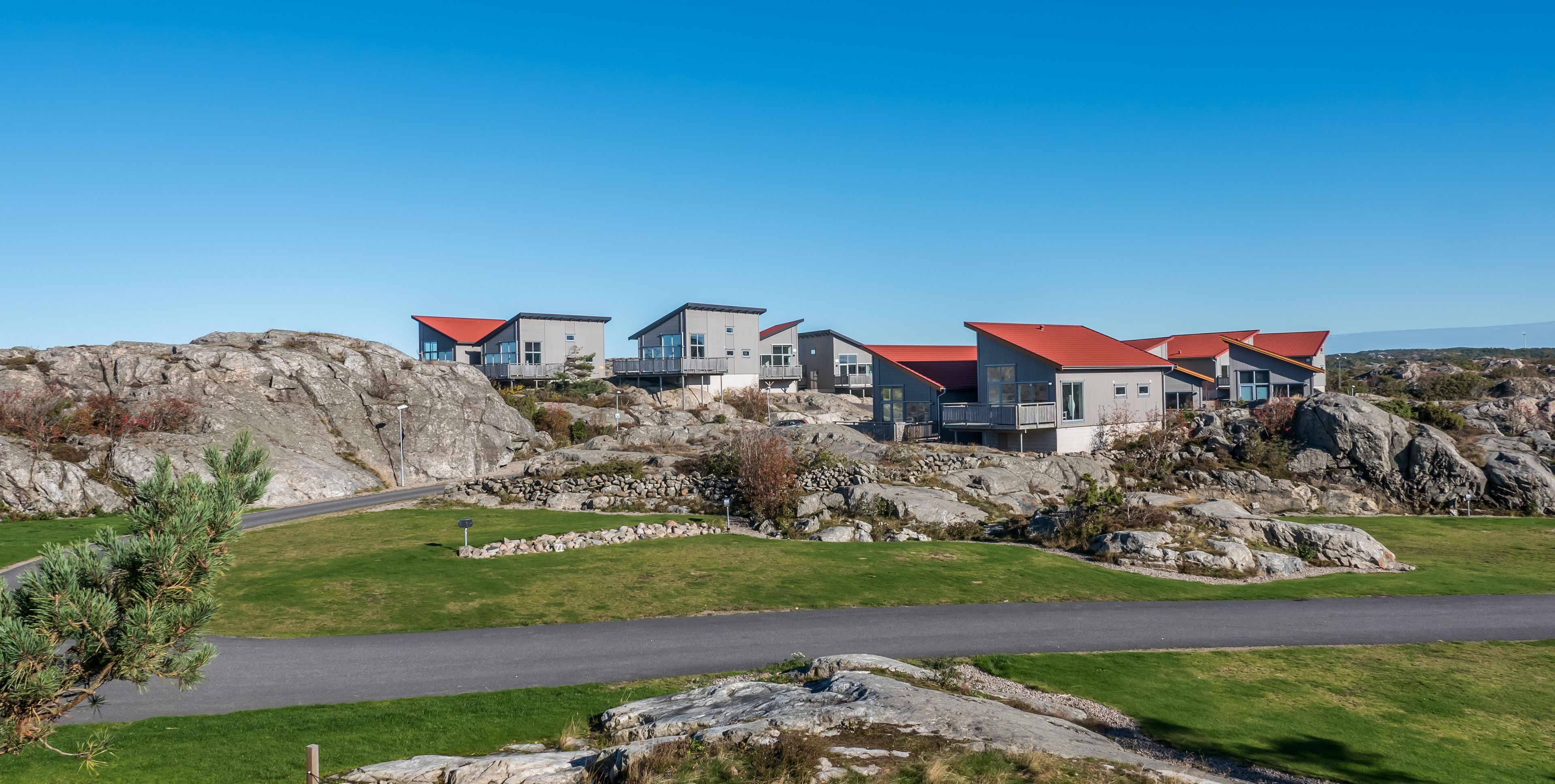 En rad moderna hus med röda tak, som kontrasterar mot ett bergigt landskap.
