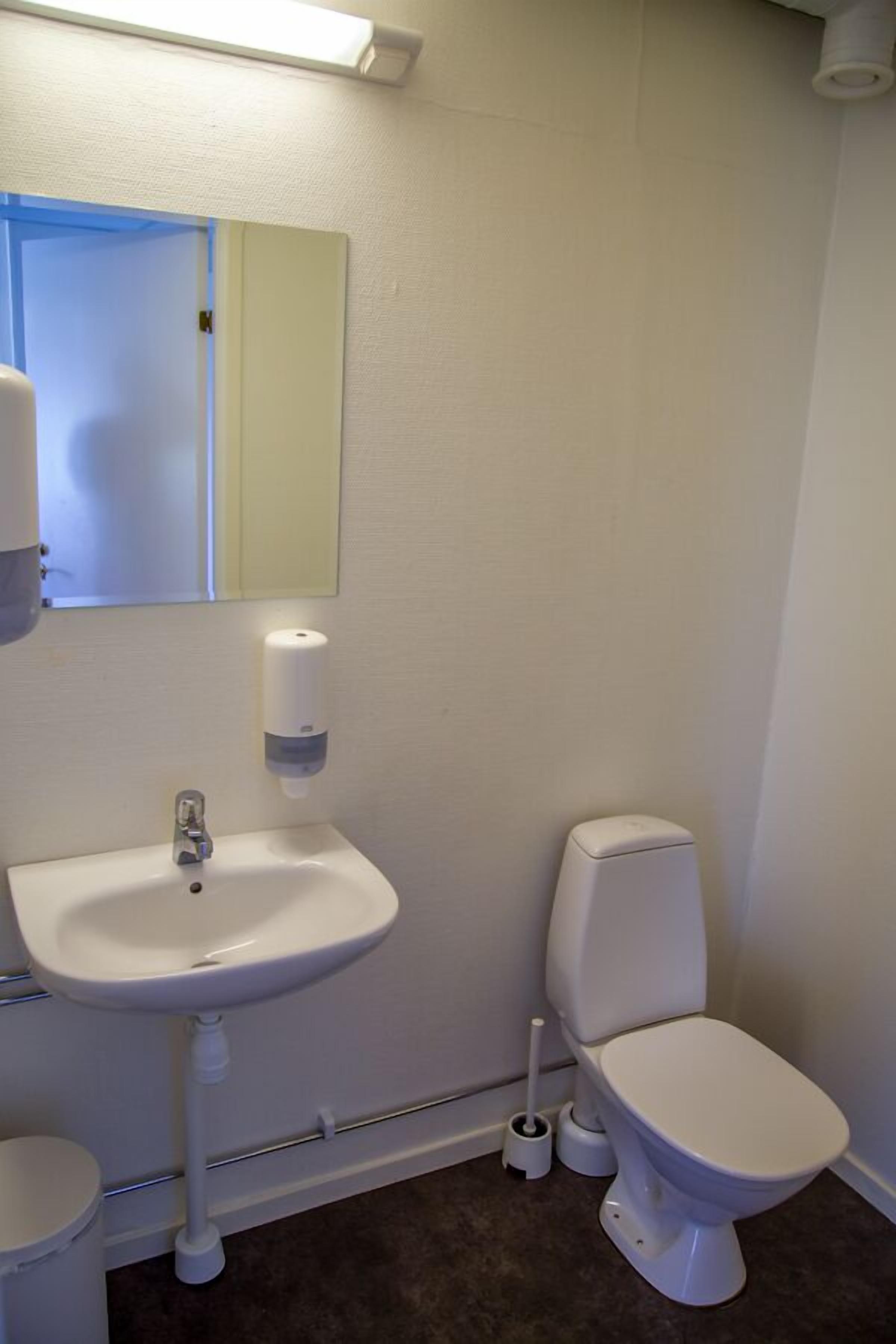 A bathroom with a white sink, toilet, and mirror.
