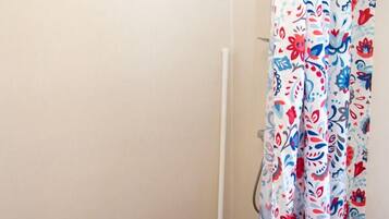 A bathroom with a shower curtain featuring a floral pattern, a white toilet, and a blue floor.