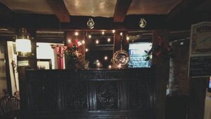 A dimly lit restaurant with wooden furniture and a dark, ornate partition. - The Halfway House Inn (Bridgnorth)