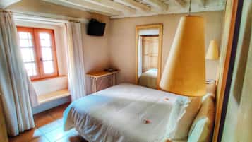 Un dormitorio con una cama, una mesita, una ventana con cortinas y un ventilador de techo.